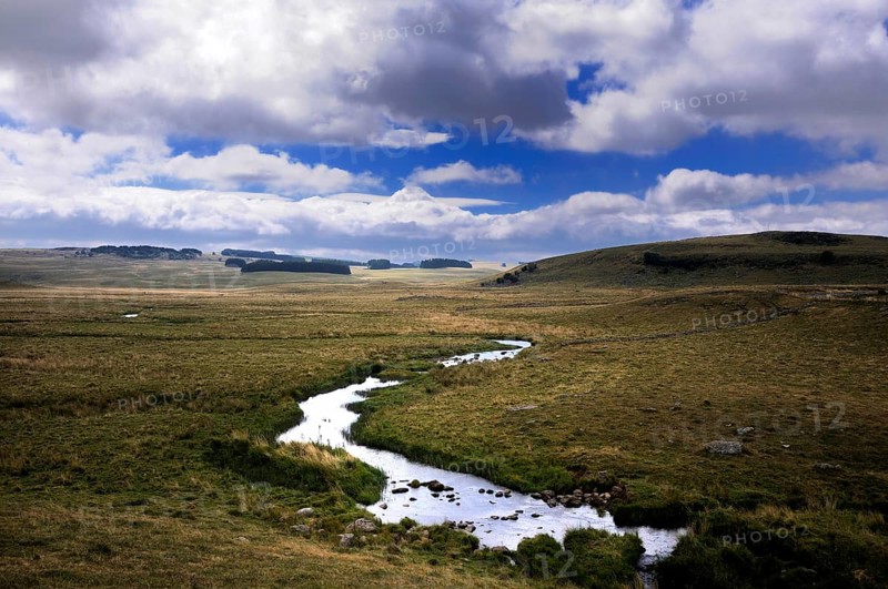 Small stream crossing pasture under a stormy sky