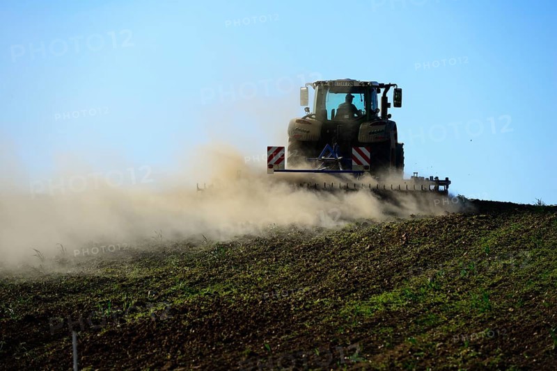 Farmer harrows field with tractor