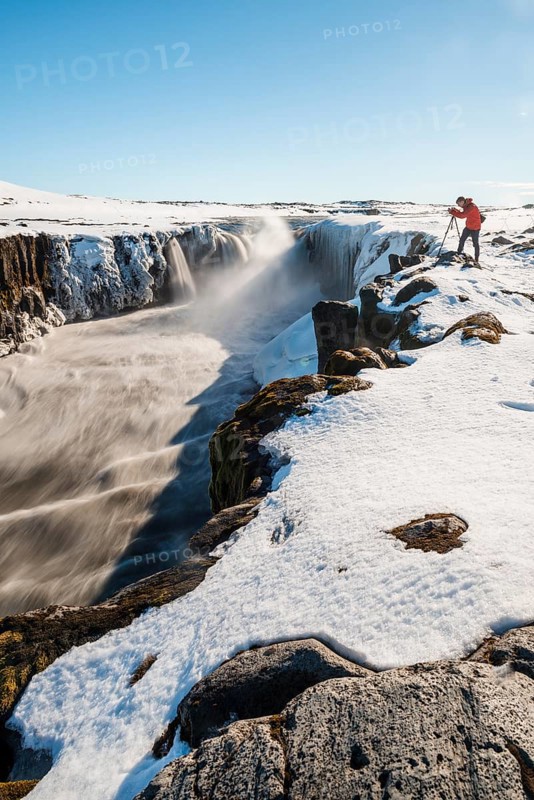 Photographing man at the edge of the Selfoss waterfall in winter