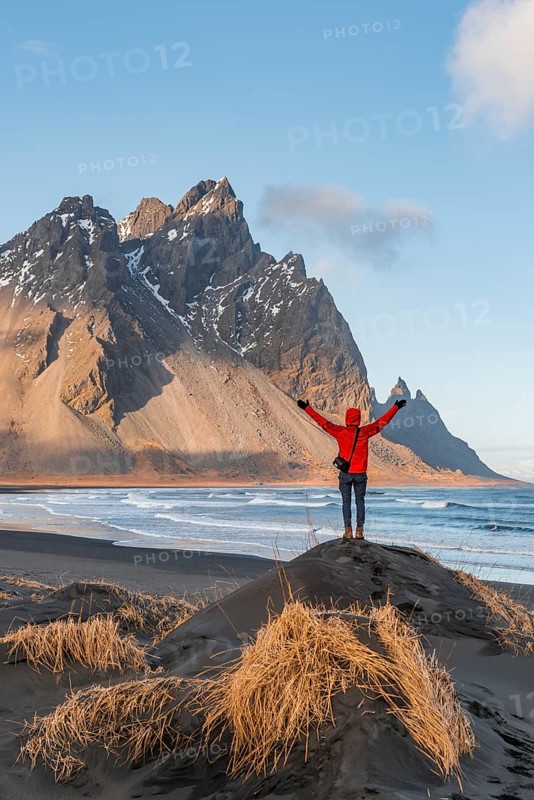 Man in red jacket stretches arms into the air