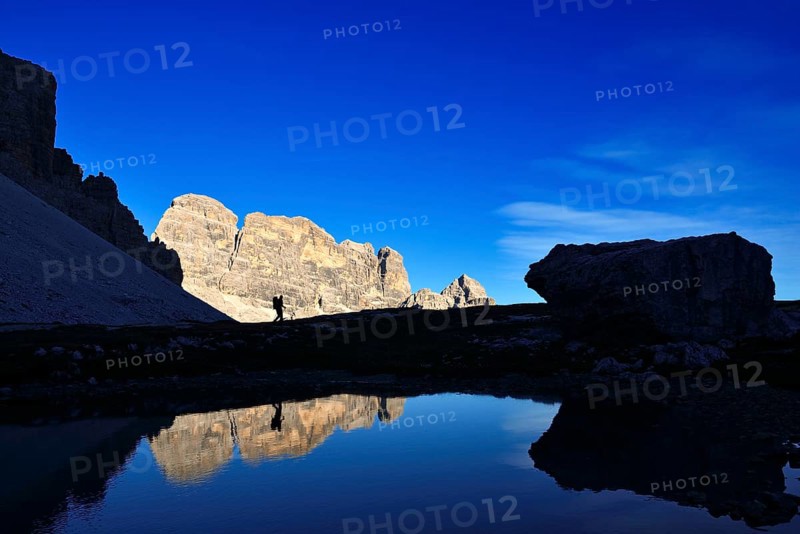 Hiker on the lake in the backlight