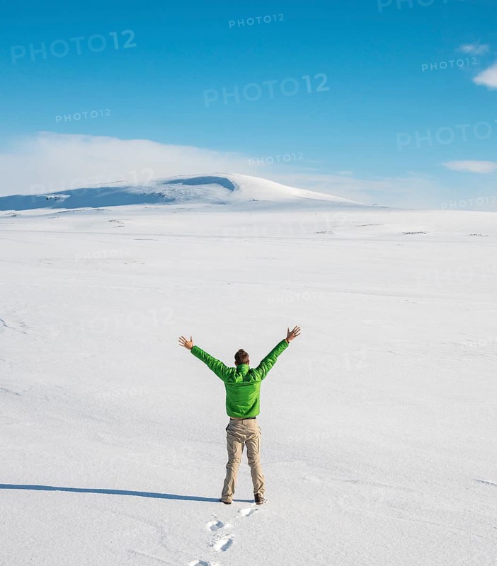 Young man stands alone in snowy landscape