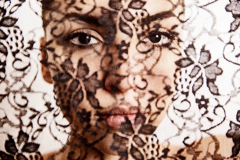 Face of a beautiful woman behind a transparent cloth with floral pattern