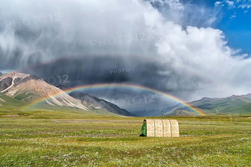 Tent under a rainbow over meadow