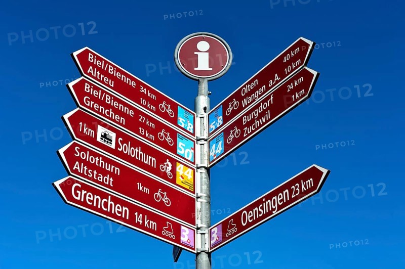 Various signposts for cycling tours and inline skating in front of blue sky