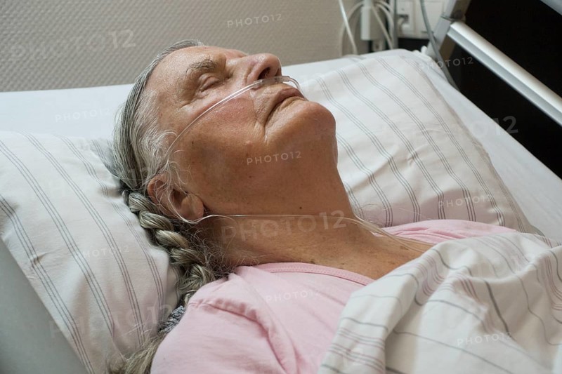 Sleeping senior citizen with respiratory tube in bed in hospital