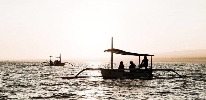 Silhouettes of outrigger boats in the ocean at sunrise