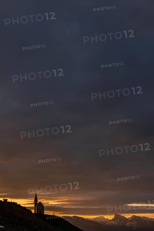 Latzfonser cross chapel at sunrise with dramatic clouds and South Tyrolean mountains