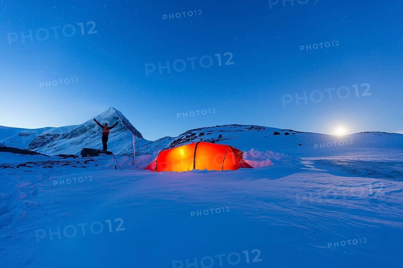 Tent with person at full moon in the snow