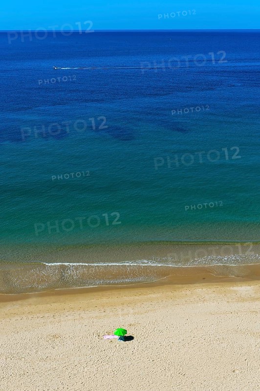 Solitary parasol on an empty sandy beach near Praia da Luz