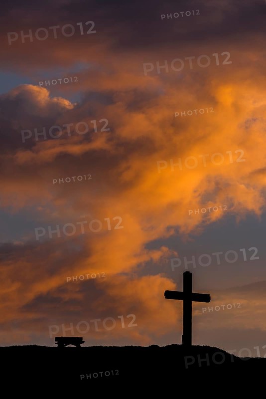 Summit cross with bank and dramatic clouds at sunrise