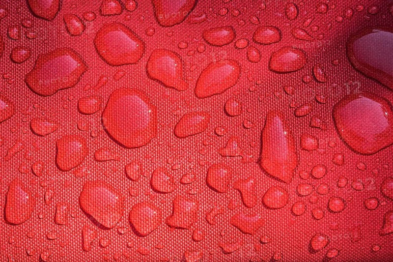 Close-up of raindrops on surface of water resistant red canvas material