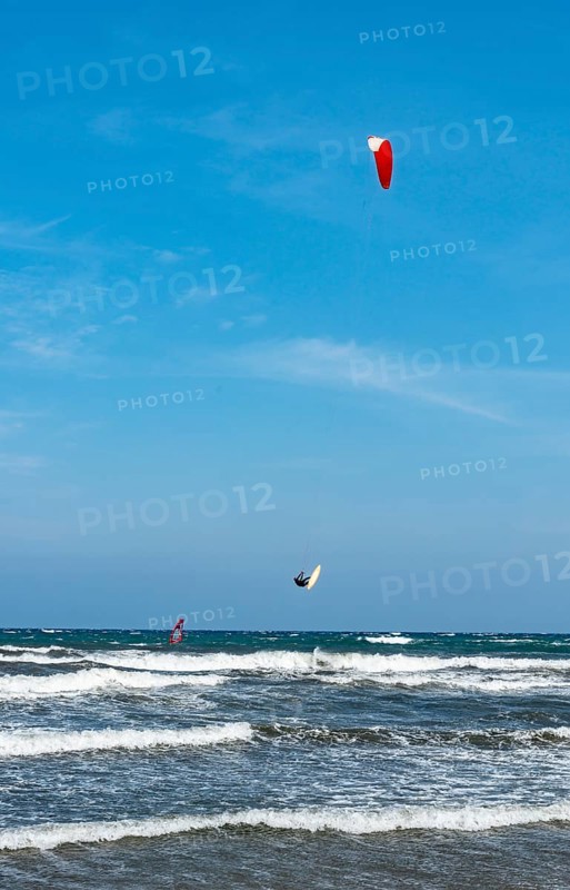 Kitesurfer in the air over sea with waves