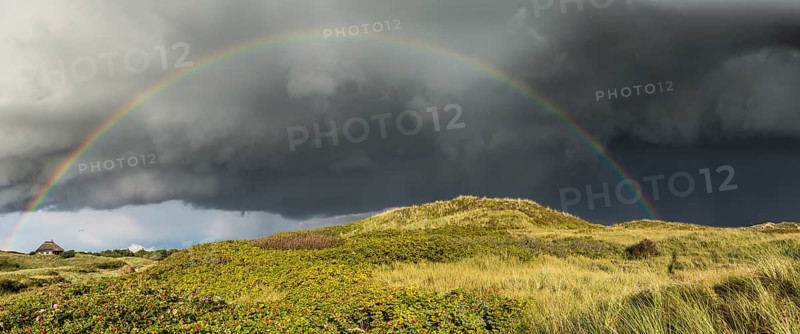 Rainbow with dramatic rain clouds over dune landscape