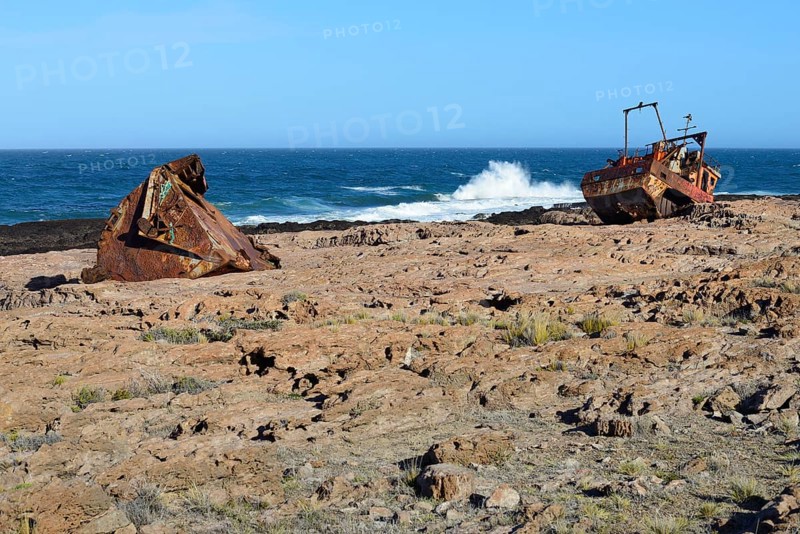Rusty wreck of a fish trawler on the rocky shore