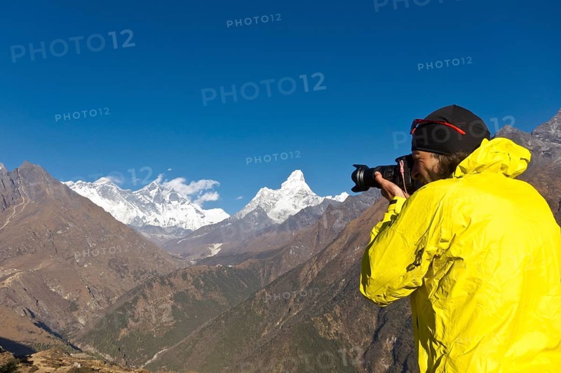 Photographer with yellow jacket taking a photograph of Mount Everest Mountain