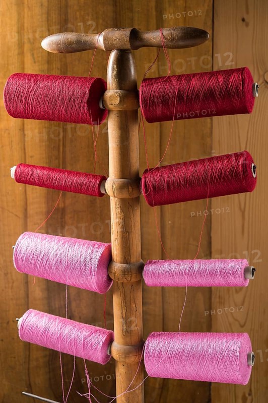 Thread stand in front of wooden wall with cotton thread reels