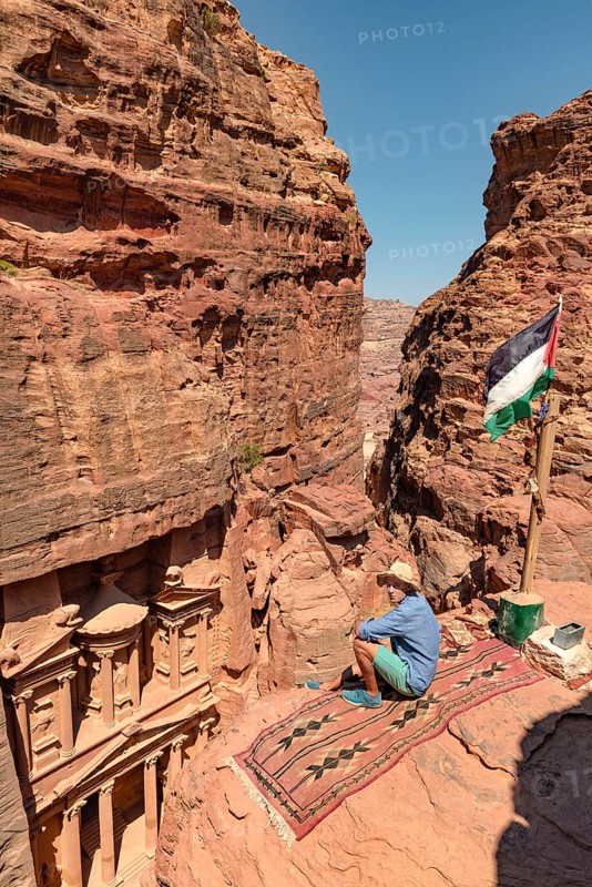 Tourist sits on a carpet and looks from above into the gorge Siq
