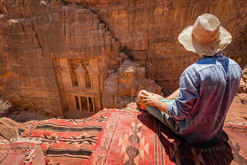 Tourist with sun hat sitting on carpet
