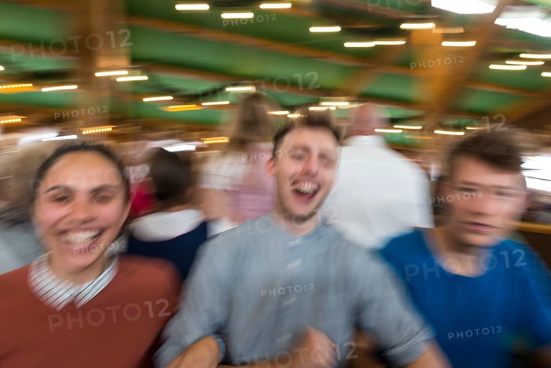 Three young people celebrate happily in a beer tent