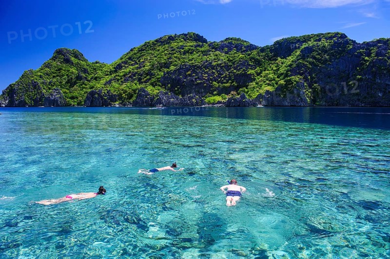 Tourists snorkeling in the crystal clear water in the Bacuit archipelago