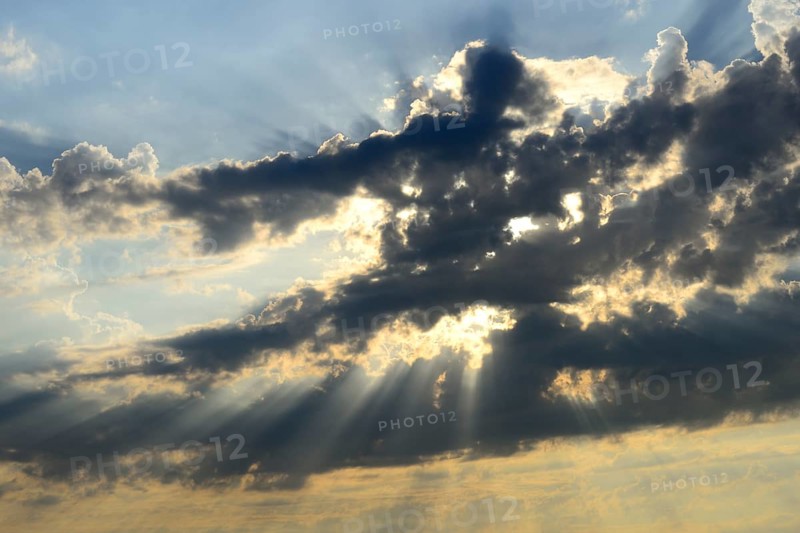 Sun shining behind dark clouds
