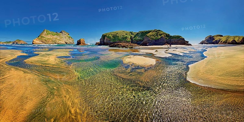 Sandy beach with receding water and rocky island in the surf