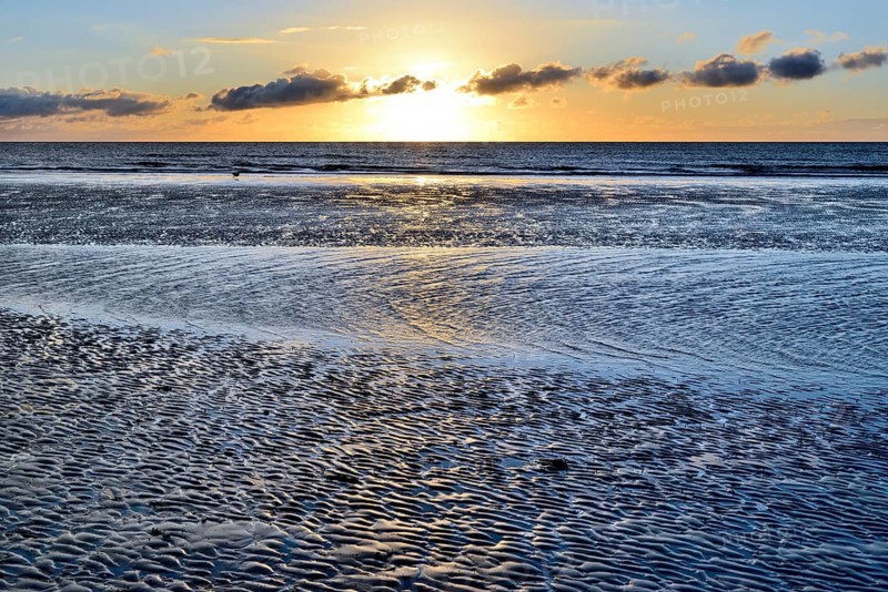 Sunset on sandy beach with wave-like structures