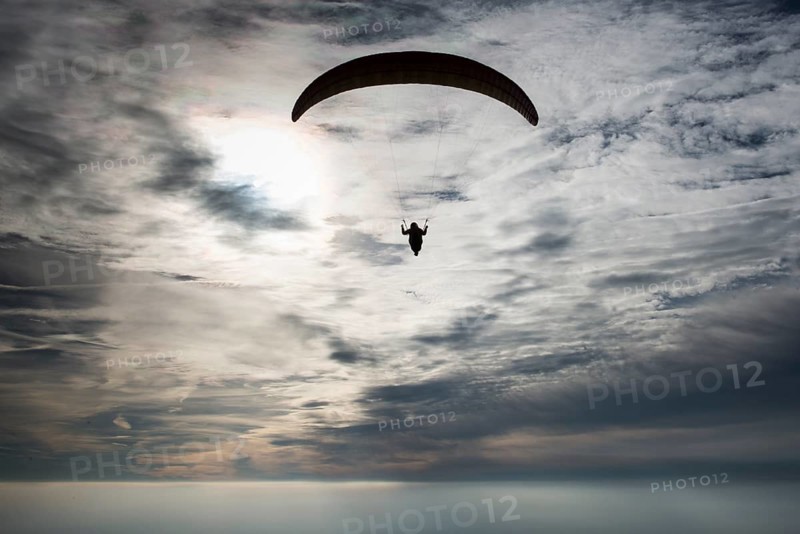 Paraglider against cloudy sky