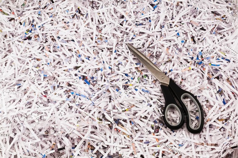Black scissors on top of strips of shredded paper