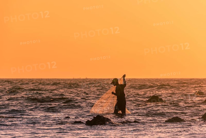 Local fishermen with fishing net in backlight