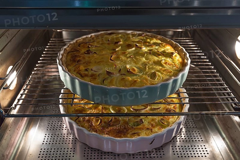 Two baked leek quiches in round form in the oven