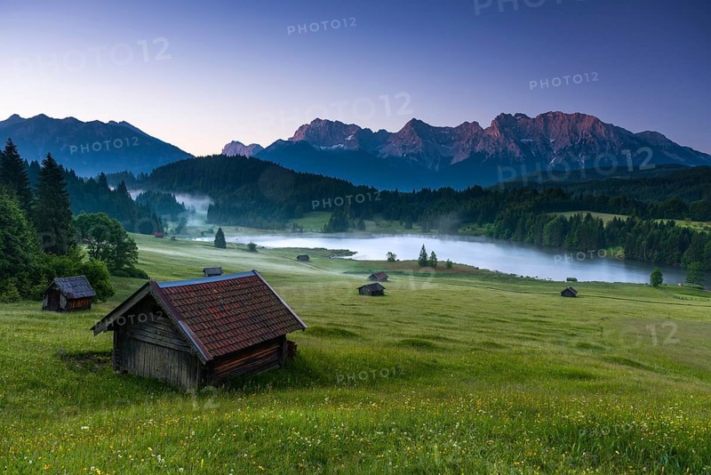 Small cabin on mountain meadow at forest edge