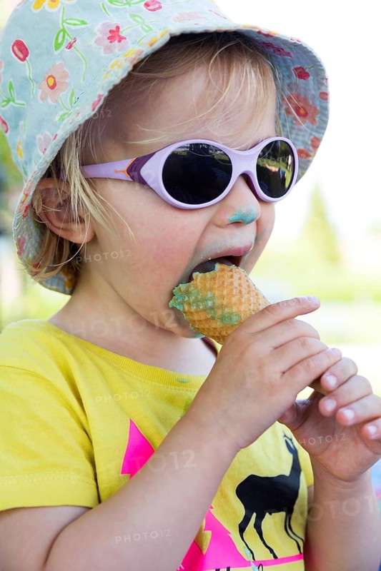 Toddler with sunglasses licking ice cream