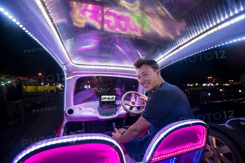 Young man driving a colorful car illuminated with LEDs