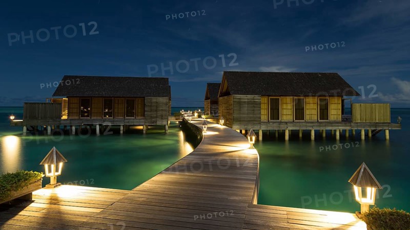 Wooden huts on stilts in lagoon at night