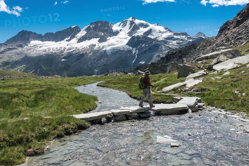 Hiker crosses mountain stream