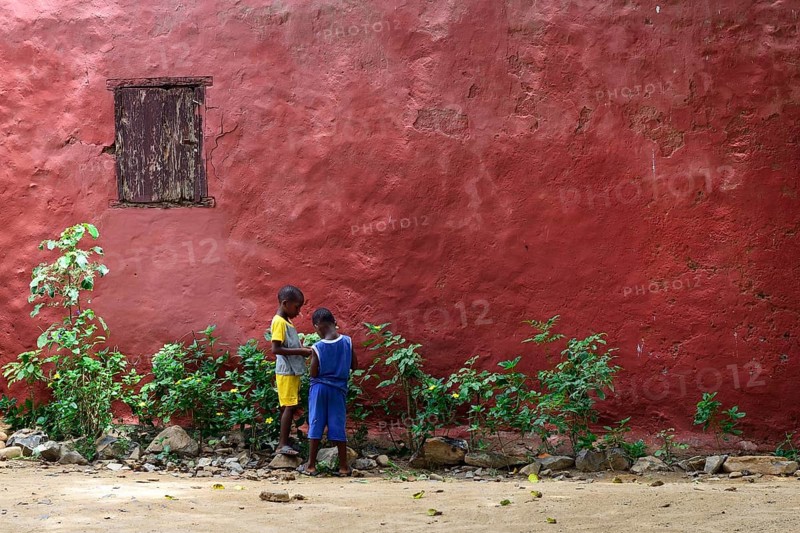 Two children in front of a red house facade