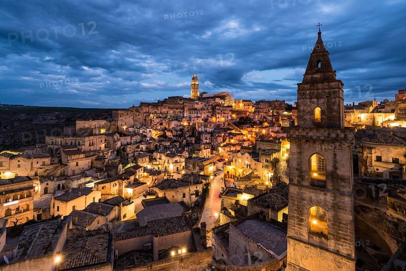 Church tower San Pietro Barisano in front of illuminated old town with cathedral