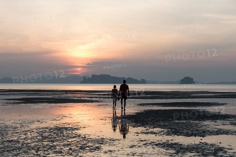 Couple at low tide on the beach at sunset