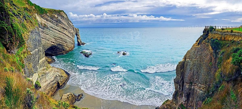 Steep cliff with arch of rock and small sandy beach