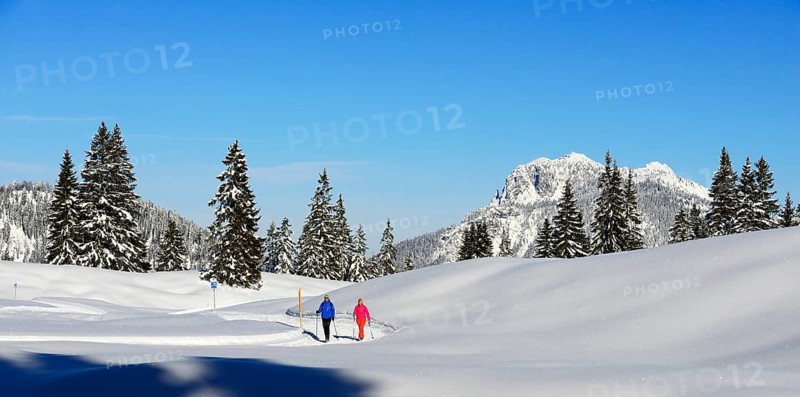 Two hikers walk through snow-covered mountain scenery