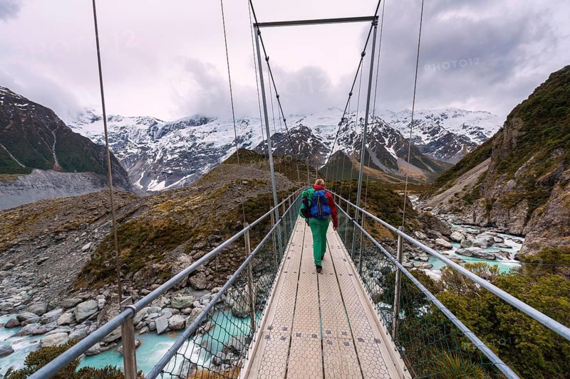 Hiker proceeds suspension bridge over River Hooker