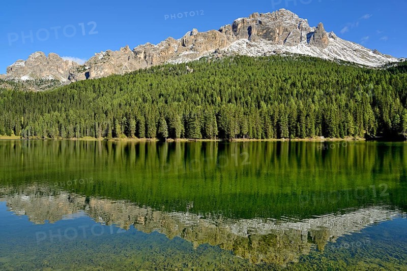 Mountain range Cadini di Misurina and dense mountain forest are reflected in Lake Misurina