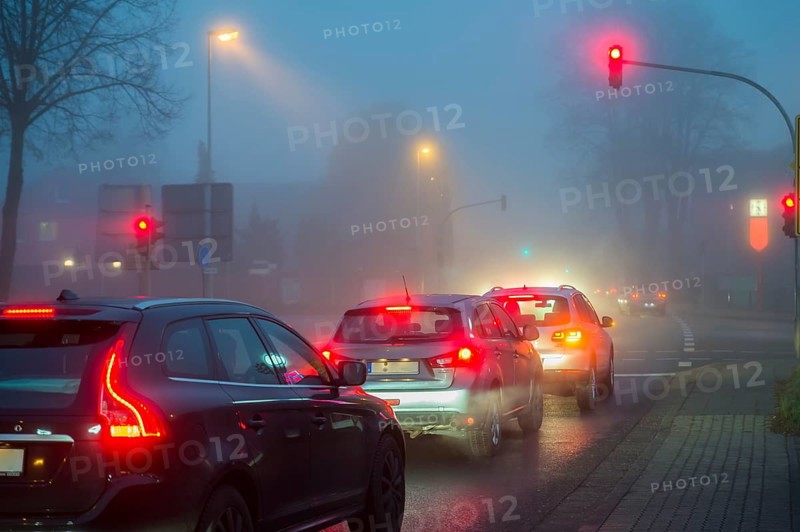 Cars at a red light in fog at night