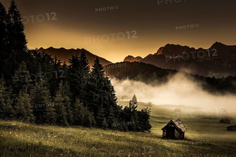 Small cabin on mountain meadow at forest edge