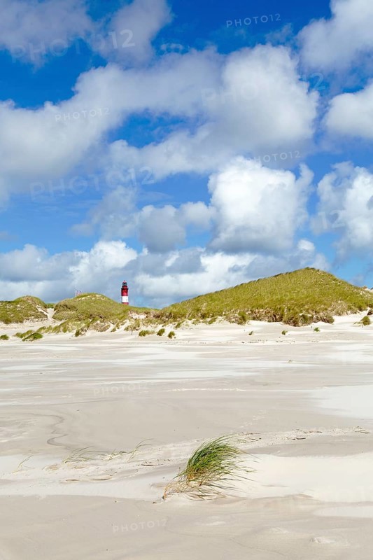 Dunes with lighthouse and cloudy sky