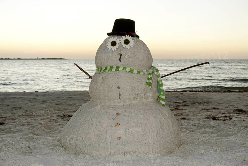 Snowman made of sand on the beach in the evening light