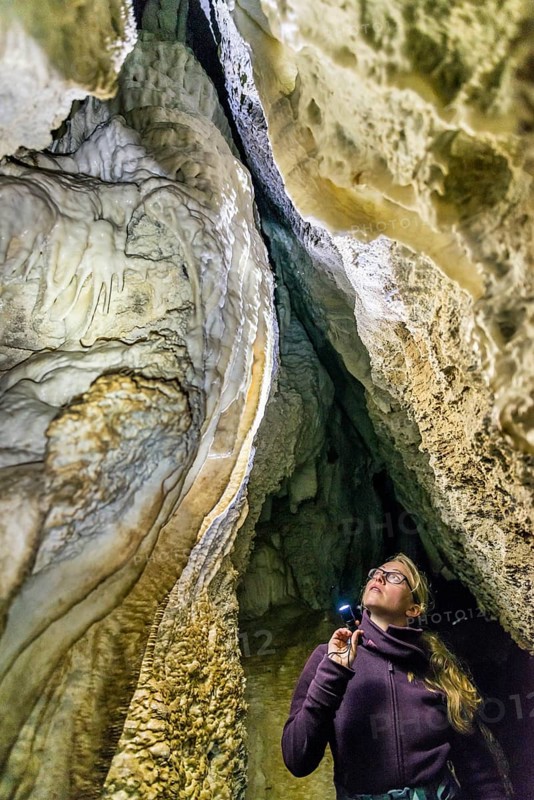 Woman lighting a cave with flashlight