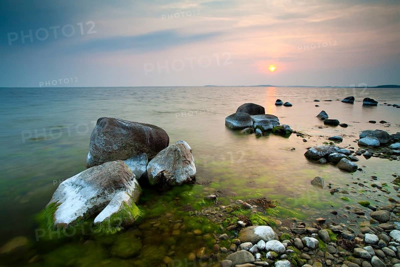 Coastline with big boulders on beach at sunset